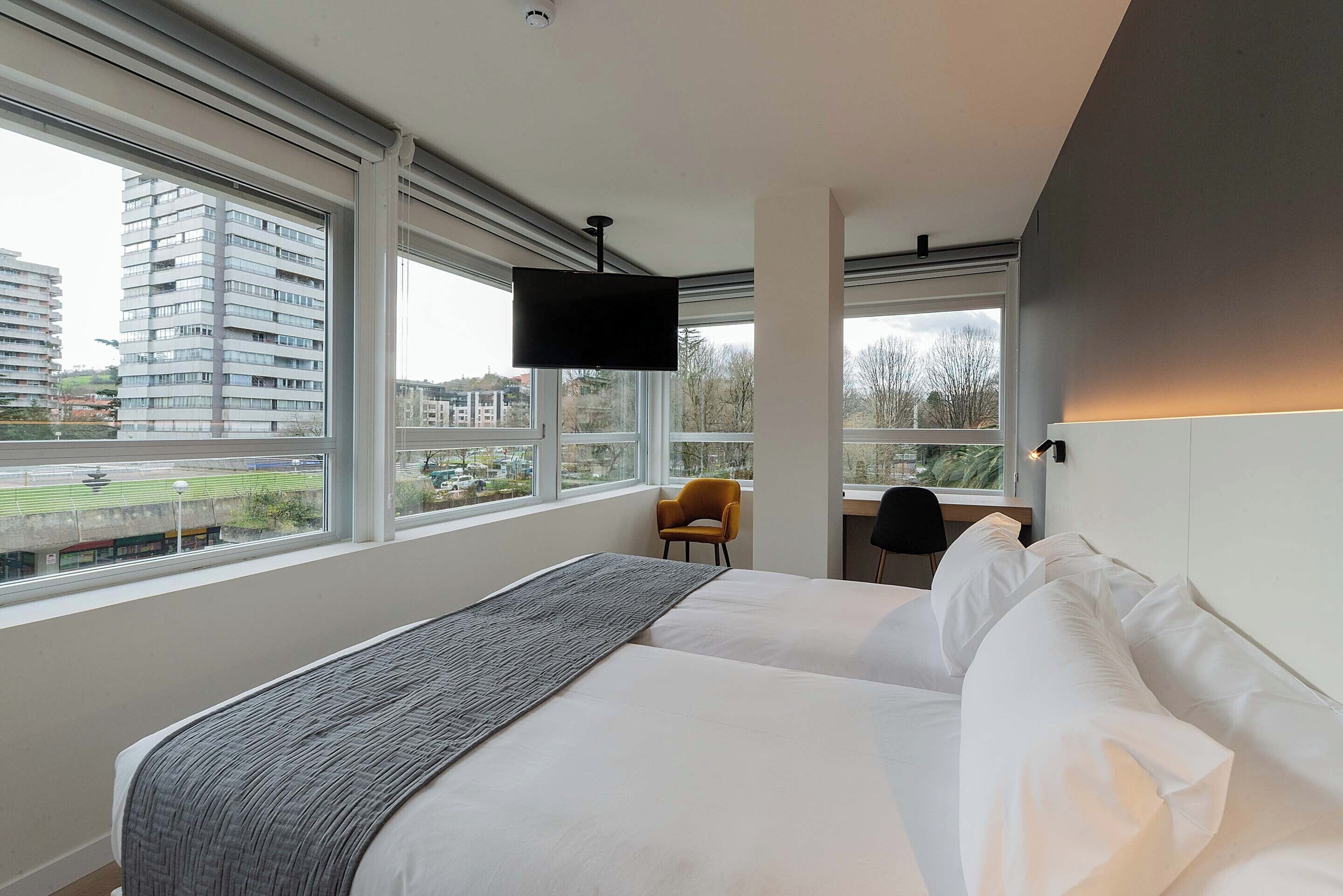 Een moderne hotelkamer met een groot bed, een bureau en een televisie.