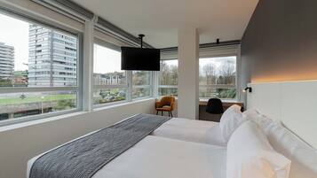 Een moderne hotelkamer met een groot bed, een bureau en een televisie.