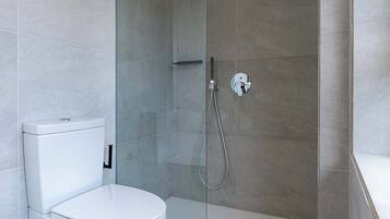 A modern bathroom with a glass-enclosed shower, a white toilet, and a tiled floor.