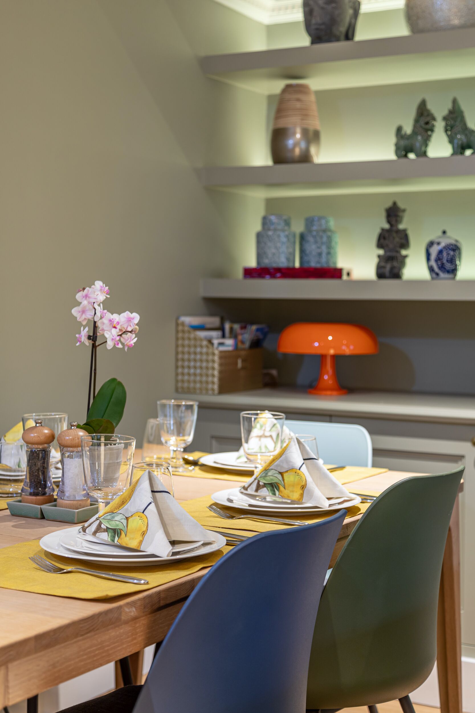 A dining table set with plates, glasses, and a centerpiece of pink orchids.