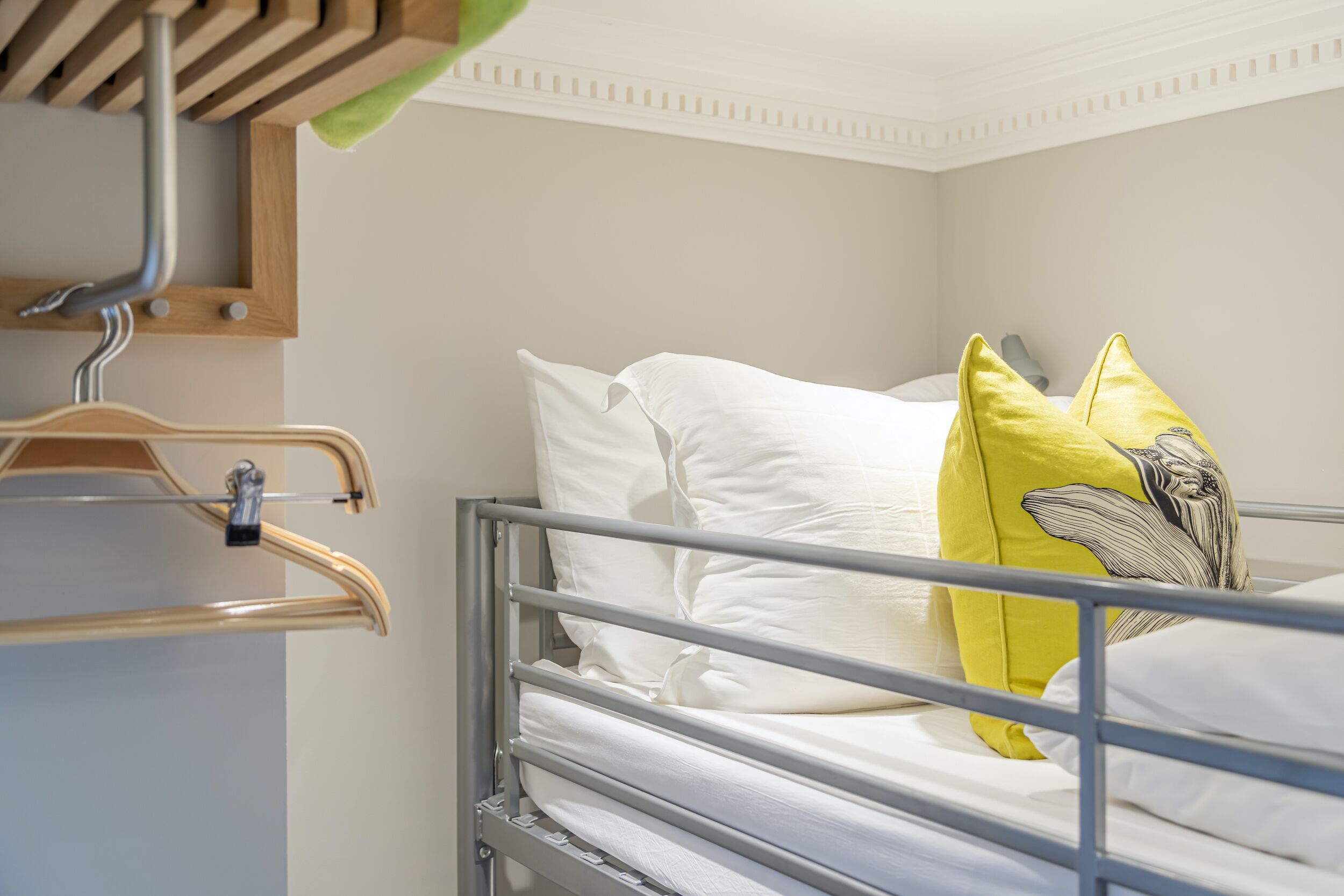 Een stapelbed met wit beddengoed en een geel kussen met walvisprint.