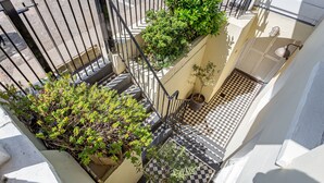 A narrow outdoor corridor with a checkered floor, potted plants, and a metal railing. - Beaches Brighton 1 (Brighton)