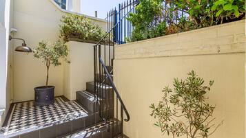 A staircase with black and white checkered tiles, a black metal railing, and potted plants.