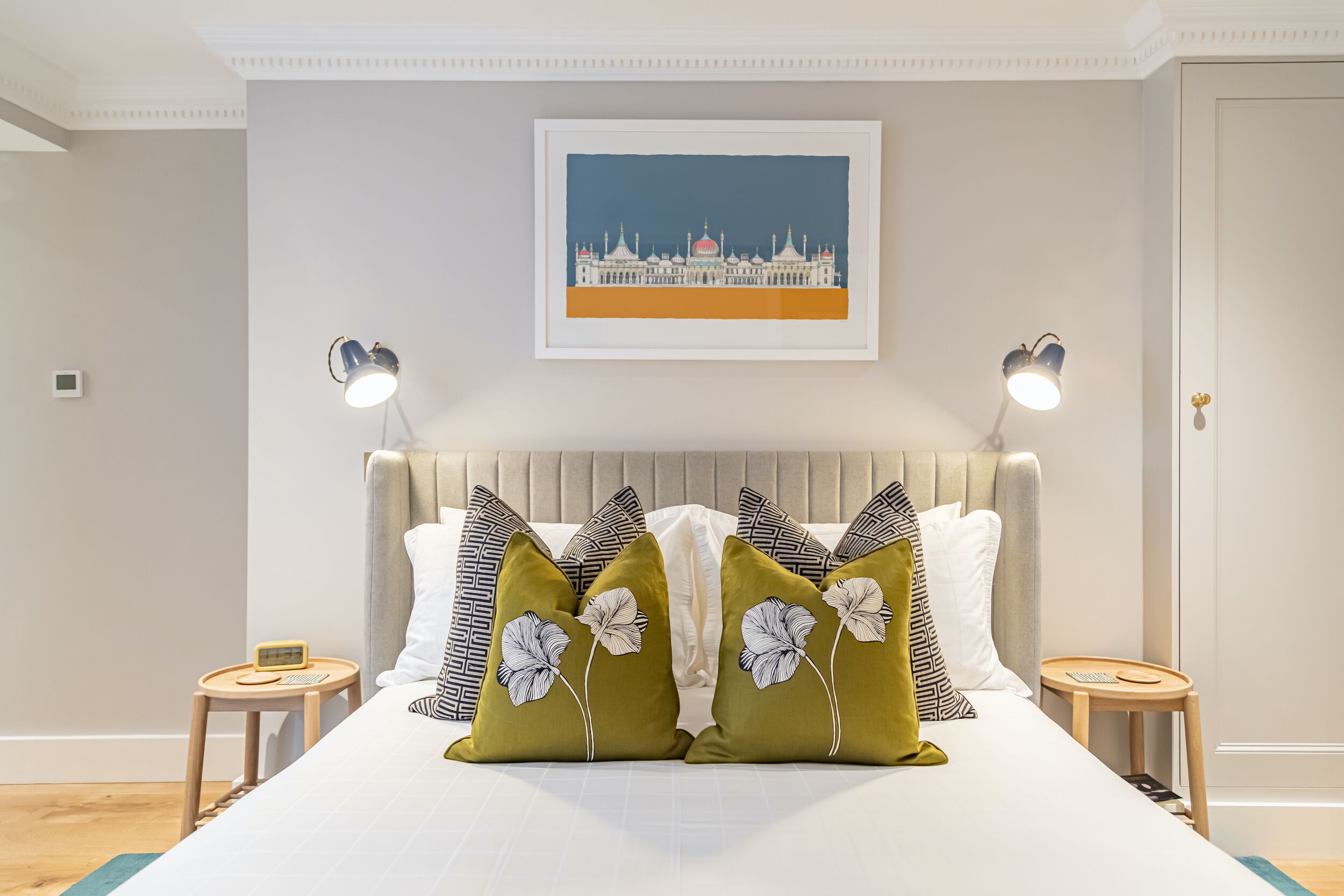 Een netjes ingerichte slaapkamer met een groot bed, een lijst met een foto aan de muur en bedlampjes.