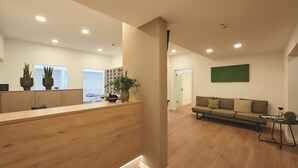 A modern reception area with a wooden desk, potted plants, and a green wall. - City Appartementhotel (Bad Fuessing)
