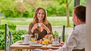 A breakfast setting with a table set for two, including plates, cups, and a pitcher of orange juice. - City Appartementhotel (Bad Fuessing)