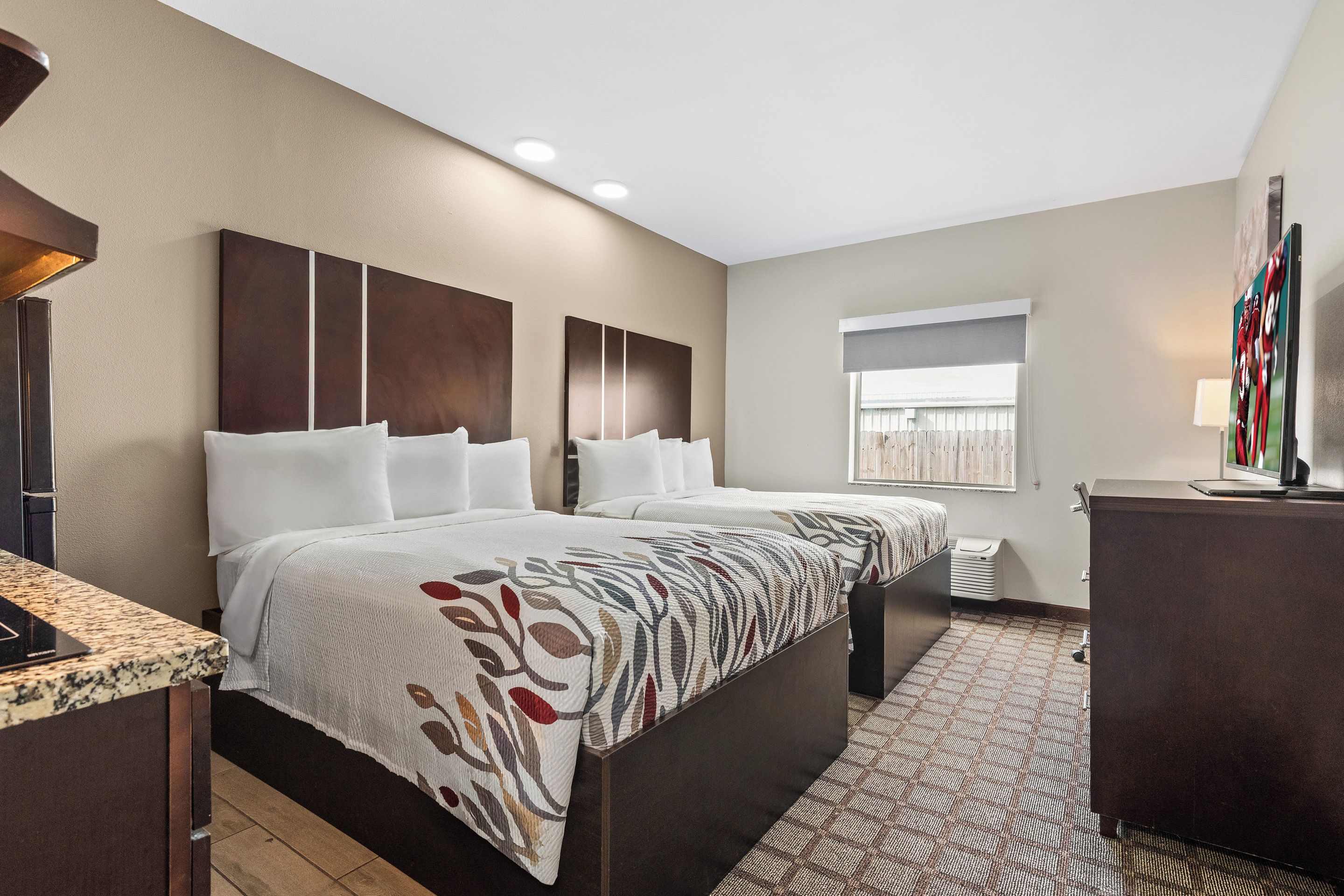 A hotel room with a large bed, a desk, and a window with curtains.