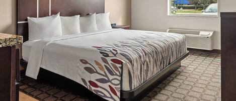 A hotel room with a large bed, a headboard, a window with a view of the outside, and a radiator.