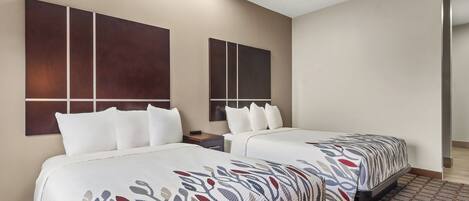 Quarto de hotel com duas camas, uma grande pintura abstrata na parede e um tapete estampado.