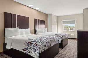 Quarto de hotel com duas camas, uma janela grande e vista para o exterior.