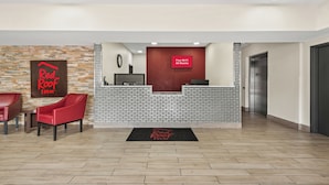 L’espace d’accueil d’un hôtel Red Roof Inn, avec un mur en briques, un comptoir d’accueil et un panneau numérique indiquant que le Wi-Fi est gratuit dans toutes les chambres.