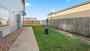 A backyard with a wooden fence, a concrete pathway, and a grassy area. - Red Roof Inn Baton Rouge (Baton Rouge)