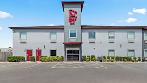 A Red Roof Inn with a modern design, featuring a prominent red roof and a large entrance with a glass door. - Red Roof Inn Baton Rouge (Baton Rouge)