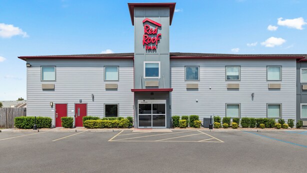 Un hôtel Red Roof Inn au design moderne, caractérisé par un toit rouge bien visible et une grande entrée dotée d’une porte en verre.