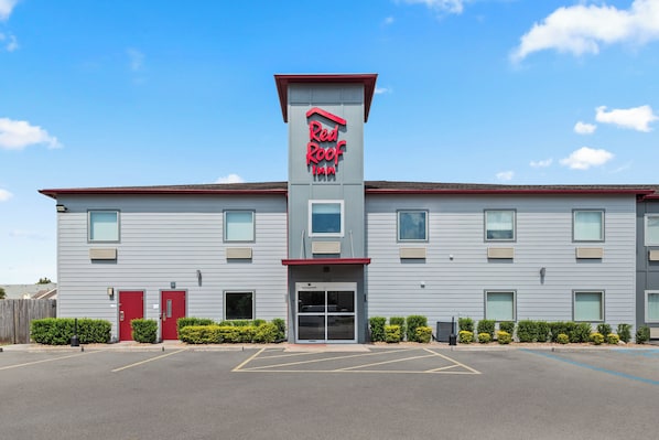 A Red Roof Inn with a modern design, featuring a prominent red roof and a large entrance with a glass door.