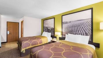 Quarto de hotel com duas camas, uma porta de madeira e duas grandes pinturas de paisagens nas paredes.