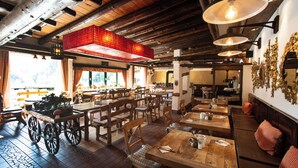 Un restaurante con mesas y sillas de madera, techo de tejas rojas y lámparas colgantes.
