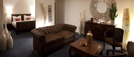Una sala de estar con un sofá de cuero marrón, una mesa de centro de madera y un espejo decorativo.