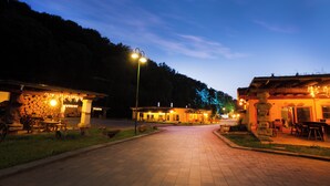 Un camino pavimentado que lleva a un edificio con terraza y un muro de piedra.
