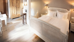 Un dormitorio con una cama grande, un armario de madera y una pequeña mesa con sillas.