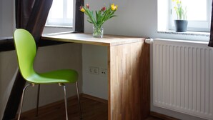A room with a wooden desk, a green chair, and a window with a view of the outside. - Pension Sackpfeifenmühle (Erfurt)