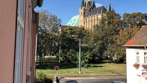 A historic building with a green roof and multiple spires, surrounded by trees and a street. - Pension Sackpfeifenmühle (Erfurt)