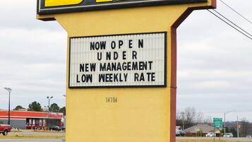 A sign for Budget Inn stating it is now open under new management with a low weekly rate.