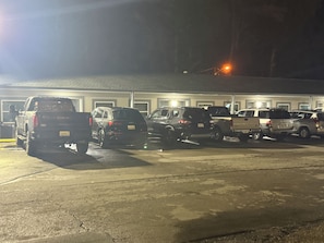 A parking lot with several vehicles parked in front of a building with a flat roof.
