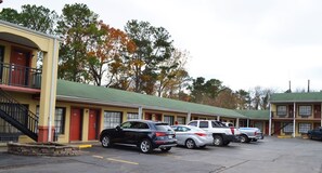 A motel with a green roof, multiple rooms, and a parking lot with several cars. - Budget inn (Russellville)