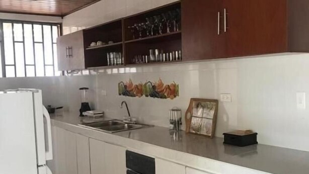 A kitchen with white cabinets, a built-in sink, and a wooden ceiling. - Casa Bella San Andres (San Andrés)