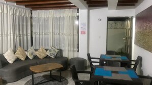 A living room with a sofa, coffee table, and dining table with chairs. - Casa Bella San Andres (San Andrés)