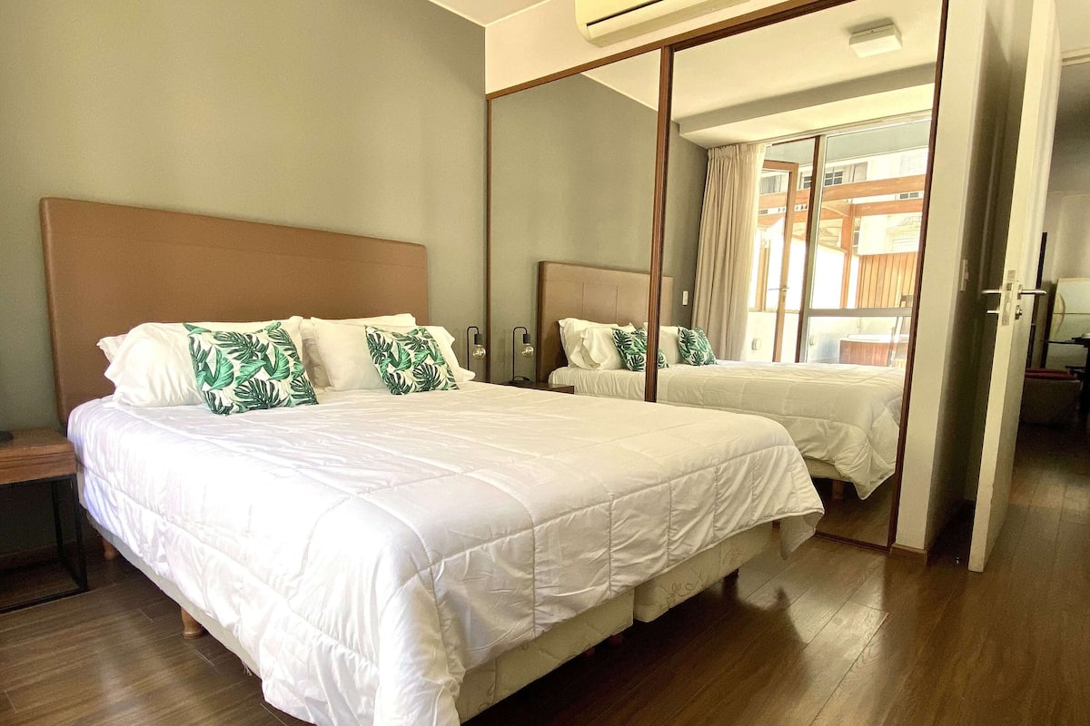 Een hotelkamer met een groot bed, een houten hoofdbord, een spiegel en een houten vloer.