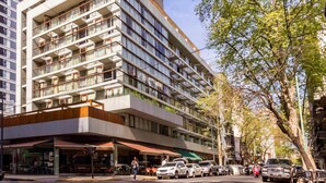 Een meerlaags hotel met een modern architectonisch ontwerp, met balkons en een restaurant op de begane grond.