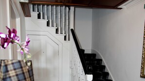 A staircase with black and white checkered carpet, a white railing, and a dark wooden floor. - Richmond House Hotel (Fort Augustus)