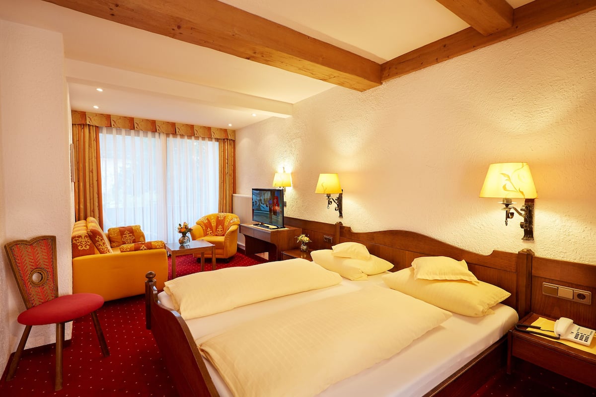 Une chambre d’hôtel avec un grand lit, un canapé, un bureau avec une télévision et un téléphone.