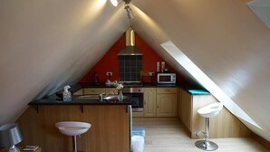 A compact kitchen with a central island, a microwave, and a stove. - Pentre Riding Stable and Accommodation (Swansea)