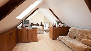 A loft bedroom with wooden cabinets, a bed, a TV, and a sofa. - Pentre Riding Stable and Accommodation (Swansea)