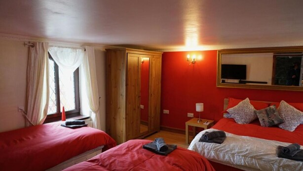 Une chambre avec deux lits, une armoire en bois, un miroir et une fenêtre avec des rideaux.