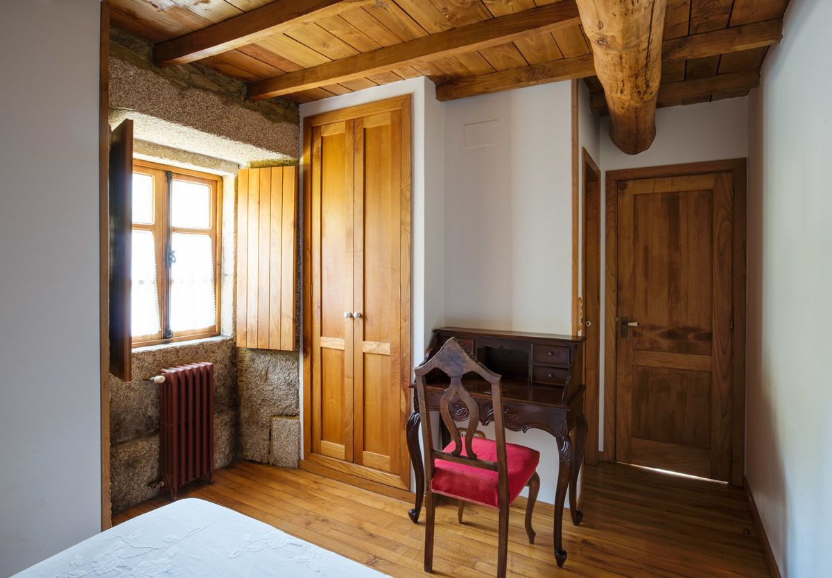 Une pièce avec un plafond en bois, des murs en pierre, un bureau en bois, une chaise et un radiateur.