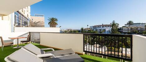 A balcony with two sun loungers, a small table, and a chair.
