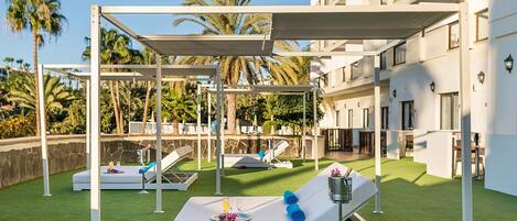 Eine Dachterrasse mit Liegestühlen, einer Pergola und einem Poolbereich.