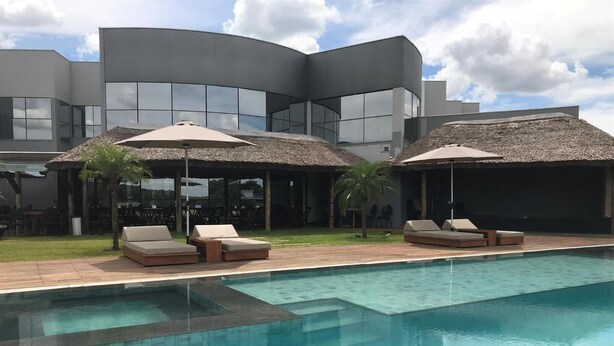 Un hotel moderno con piscina, sillones de descanso y sombrillas de paja.
