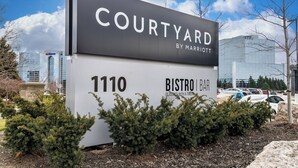 A sign for 'Courtyard by Marriott' with the address '1110 Bistro Bar' and a view of the surrounding area including a parking lot and buildings. - Courtyard by Marriott Burlington (Burlington)