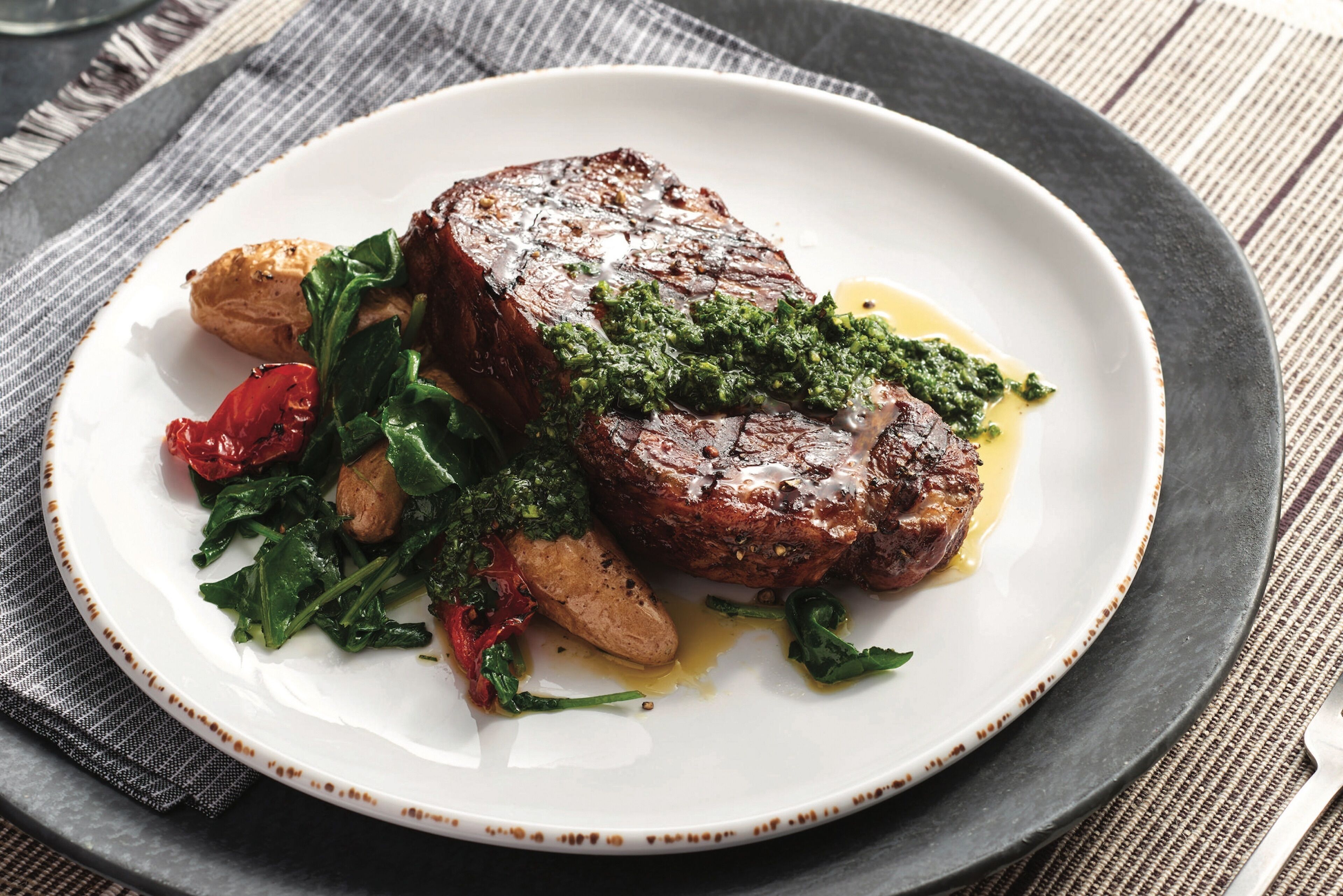 Een bord eten met steak, groenten en geroosterde aardappelen.