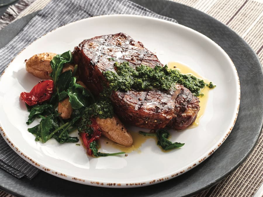 Een bord eten met steak, groenten en geroosterde aardappelen.
