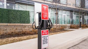 Eine Tesla-Ladestation mit Schild, das anzeigt, dass sie ausschließlich für Gäste ist und eine Kfz-Kennzeichenregistrierung an der Hotelrezeption erfordert.