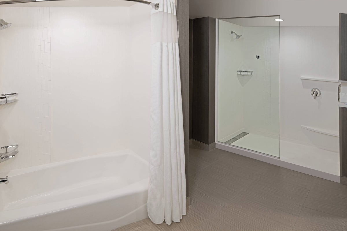A modern bathroom with a bathtub, a glass-enclosed shower, and a vanity with a mirror.