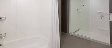 A modern bathroom with a bathtub, a glass-enclosed shower, and a vanity with a mirror.