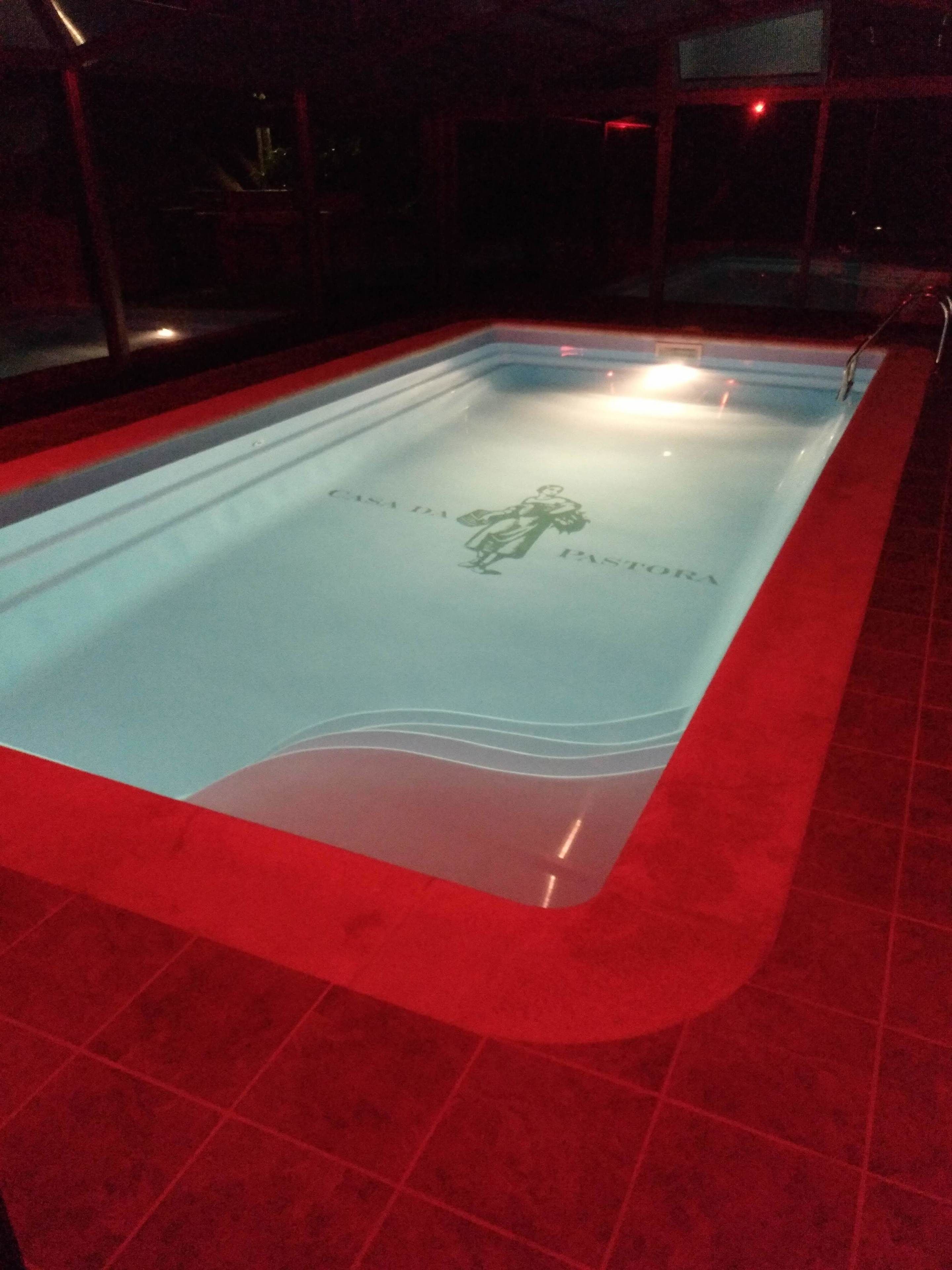 A swimming pool with a logo and text, surrounded by red-tiled flooring.