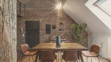 A dining area with a brick wall, a large window, and a wooden table with chairs.